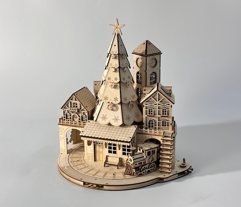 May include: A wooden Christmas village scene featuring a detailed Christmas tree, buildings, a clock tower, and a train. The scene is intricately cut from light-colored wood, with snowflake and star details.