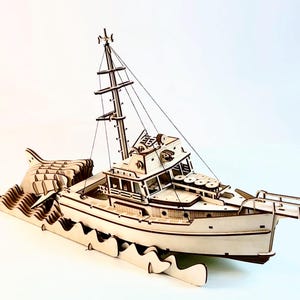 Op de afbeelding: Gedetailleerd houten model van een boot, met een mast, kajuit en ingewikkelde golfachtige basis. De boot is lichtbruin, met zichtbare details van de structuur. Het model is ontworpen als decoratief item.