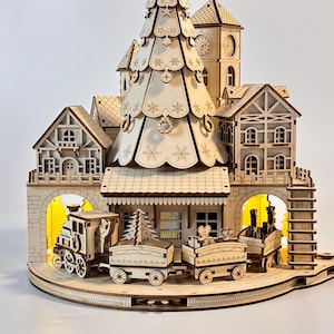 May include: A wooden Christmas village scene with a train, houses, and a clock tower. The train has several cars and is on a track. The houses have intricate details, and a large Christmas tree is in the center.