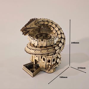 Peut inclure: Une tour à dés en bois en forme de dragon, mesurant 24,6 cm de haut, 21,5 cm de large et 19 cm de profondeur. La tour présente un design de dragon détaillé enroulé autour d'une structure à plusieurs niveaux avec un bac à dés. La tour est en bois clair.