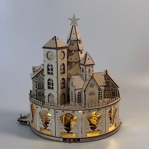 May include: A wooden Christmas village with a clock tower, houses, and a Christmas tree. The village has intricate details, including windows, doors, and decorative cutouts. It is illuminated with warm, inviting lights, and a star sits atop the tree.