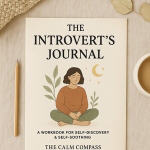 May include: A journal titled "The Introvert's Journal" with an illustration of a person meditating. The cover also includes the text "A Workbook for Self-Discovery & Self-Soothing" and "The Calm Compass". A pencil and a cup of coffee are next to the journal.