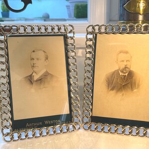 May include: Two antique silver-toned chain link picture frames, each holding a sepia-toned portrait of a man. The frames have a dark green backing. The text "ARTHUR WESTON, 84 NEWGATE ST, LONDON E.C." is visible.