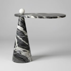 May include: A modern side table with a circular top and a conical base. The table is made of marble with a black and white pattern. A small white sphere sits on the table's edge.