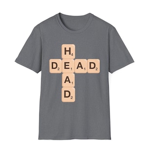 May include: A dark heather grey t-shirt with a graphic of the word "DEAD" spelled out using Scrabble tiles. The tiles are arranged in a cross shape with the "H" tile on top.