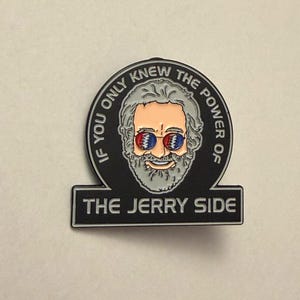 May include: A black and silver pin featuring a portrait of a man with gray hair and a beard, wearing sunglasses with a red and blue design. The pin reads "IF YOU ONLY KNEW THE POWER OF THE JERRY SIDE."