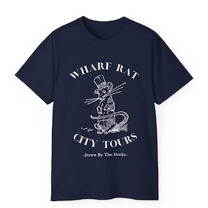Puede incluir: Una camiseta azul marino con un gráfico blanco de una rata con un sombrero de copa y el texto "WHARF RAT CITY TOURS -Down By The Docks- "