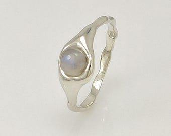May include: A silver ring with a moonstone set in a unique, organic-shaped band.