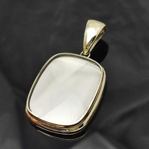 May include: A silver pendant with a clear, faceted crystal in a rectangular shape. The pendant has a simple bail for attaching to a chain.