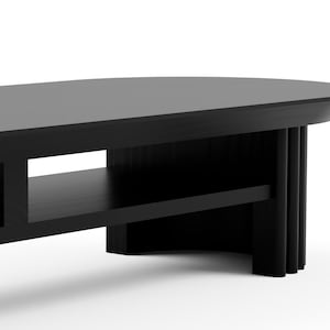 May include: Black oval coffee table with a lower shelf and a unique, fluted base.