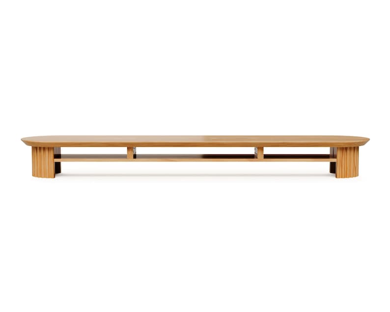 May include: A long, low, wooden bench with a light brown finish. The bench has a rounded top and is supported by two vertical, ribbed end pieces and a central support. The bench is approximately 183 cm long.