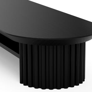May include: Black oval coffee table with a unique fluted base. The table has a shelf underneath the top.