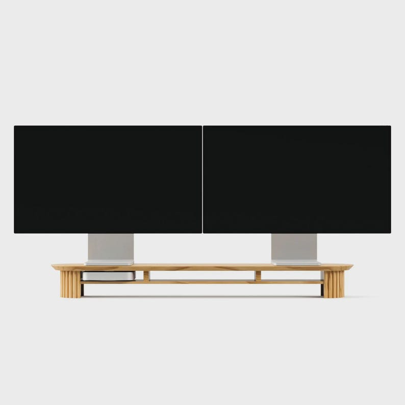 K&ouml;nnte beinhalten: Ein langer Monitorst&auml;nder aus hellem Holz mit einem geriffelten Lamellendesign an den beiden Endst&uuml;tzen. Der St&auml;nder verf&uuml;gt &uuml;ber eine horizontale Ablagefl&auml;che und tr&auml;gt zwei schwarze Computermonitore nebeneinander, mit einem kleinen silbernen Ger&auml;t darunter.