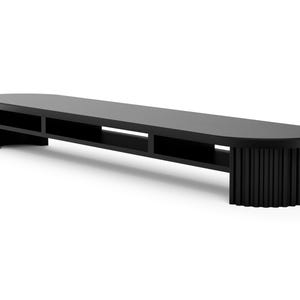 May include: Black wooden media console with an oval top and a fluted base. The console has open shelves for storage.