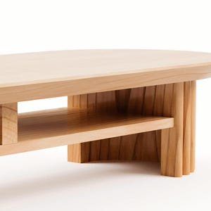 May include: A light-coloured wooden coffee table with a rounded top and a lower shelf. The table has a natural wood finish and a modern design. The legs are made of vertical wooden slats.