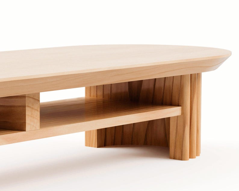 May include: A light-coloured wooden coffee table with a rounded top and a lower shelf. The table has a natural wood finish and a modern design. The legs are made of vertical wooden slats.