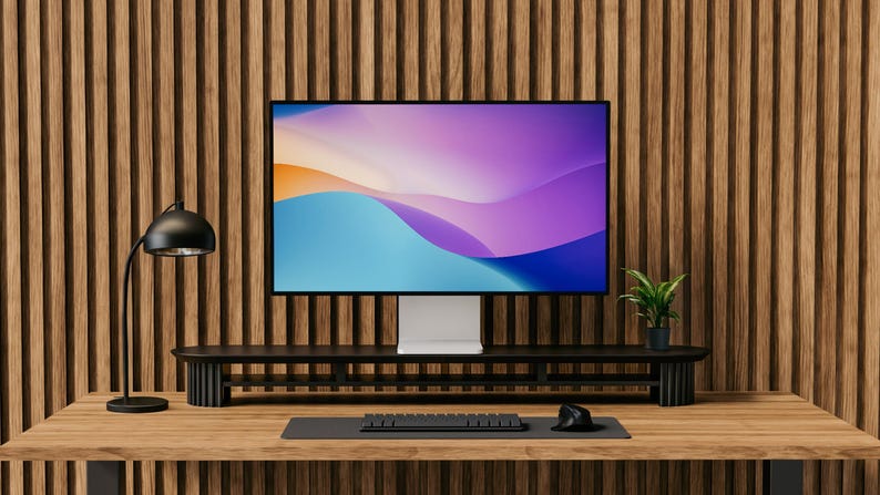 May include: A black desk lamp with a white shade sits on a wooden desk in front of a computer monitor with a colorful abstract background. The monitor is on a black stand with a black keyboard and mouse in front of it.
