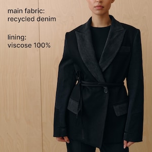 May include: A black jacket with a contrasting denim lapel and trim, featuring a belted waist and a single-button closure. The jacket is made from recycled denim and has a viscose lining. The word "JACKET" is printed at the top.