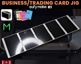 May include: A rectangular white jig with five black recessed slots for business or trading cards, labeled for 86 x 54 mm or 88 x 63 mm sizes. The text reads BUSINESS/TRADING CARD JIG, eufy Make E1, 3D JIG SOLUTIONS, and .SVG INCLUDED.