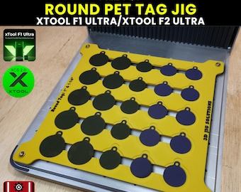 Op de afbeelding: Een gele huisdier-tagmal met een zilveren basis, ontworpen voor ronde tags van 2,5 cm en 3,2 cm. De mal bevat ruimtes voor meerdere tags in donkergroen en blauw. Tekst op de mal: "ROUND PET TAG JIG" en "XTOOL F1 ULTRA/XTOOL F2 ULTRA".