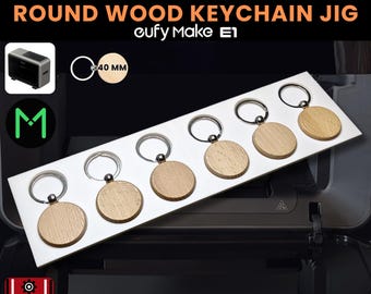 May include: A display of six round wooden keychains, each with a silver-colored ring. The keychains are 40 mm in diameter and are arranged on a white rectangular holder. The text "ROUND WOOD KEYCHAIN JIG" is displayed above the keychains.