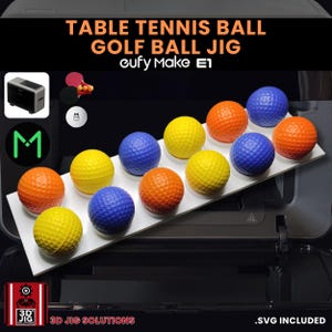 May include: A display of golf balls in various colors, including yellow, orange, and blue, arranged on a white platform. The text at the top reads "TABLE TENNIS BALL GOLF BALL JIG". The image also includes the text "3D JIG SOLUTIONS".