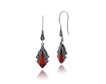 May include: A pair of silver drop earrings with red gemstone accents and marcasite detailing. The earrings have a teardrop shape and are designed in an Art Deco style.