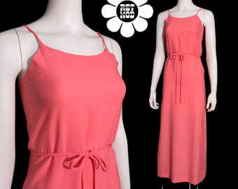 May include: A coral pink maxi dress with thin spaghetti straps and a tie at the waist.