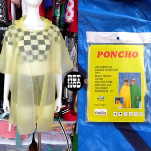 May include: Yellow vinyl poncho with a hood. The poncho is on a mannequin and has a checkered pattern underneath. The packaging for the poncho is visible and says "PONCHO" in large red letters. The packaging also says "One size fits all, durable waterproof vinyl, bright fashion colors, ideal for purse, briefcase, car, or luggage. Measures 45 x 72. 100% vinyl."