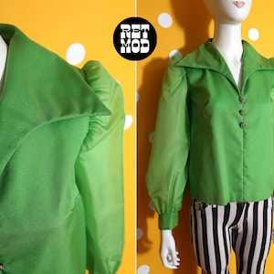 May include: A bright green blouse with a wide collar and sheer sleeves. The blouse has decorative buttons and is displayed on a mannequin. The blouse is paired with black and white striped pants.