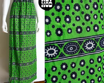 May include: A long, green skirt with a repeating pattern of black and white floral and geometric designs. The skirt is displayed on a mannequin and features an elastic waistband. The fabric has a vibrant, eye-catching appearance.