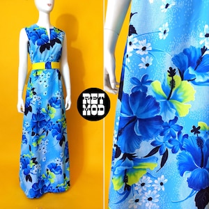May include: A sleeveless, floor-length blue dress with a vibrant floral pattern of large blue and white flowers. The dress features a yellow belt at the waist. The dress is displayed on a mannequin against a yellow background.