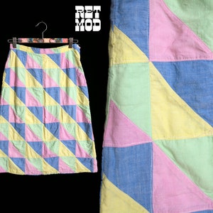 Può includere: Una gonna a patchwork con un motivo geometrico di triangoli blu, gialli, rosa e verdi. La gonna ha una cintura e un orlo dritto.