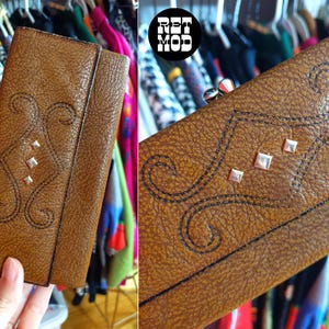 Cartera de cuero marrón estilo años 70 con diseño de volutas y ojales