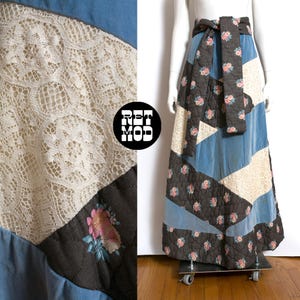 May include: A patchwork maxi skirt featuring blue, cream lace, and floral patterned panels. The skirt has a high waist and a matching tie belt. The skirt is displayed on a mannequin.