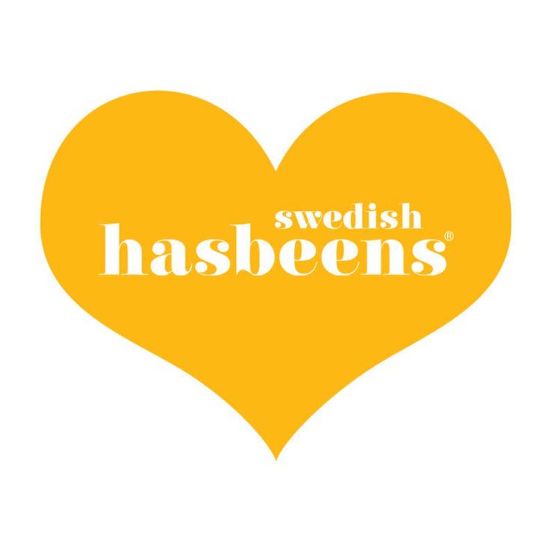 May include: A golden yellow heart shape with the words "swedish hasbeens" in white lettering. The heart is centered on a white background. The text is in a sans-serif font.