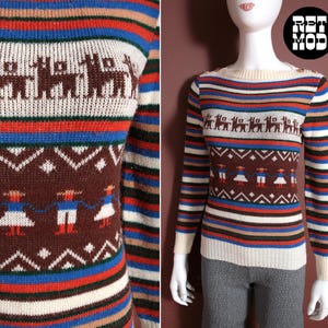 May include: A vintage-style sweater with a colorful striped pattern in blue, red, and beige. The sweater features a cream-colored yoke and cuffs, with brown geometric and animal designs. The long-sleeved sweater is displayed on a mannequin.