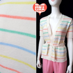 May include: A white cardigan with a V-neck and short sleeves. The cardigan has multi-colored stripes in yellow, light blue, green, and pink. The cardigan has a tie belt and two pockets.