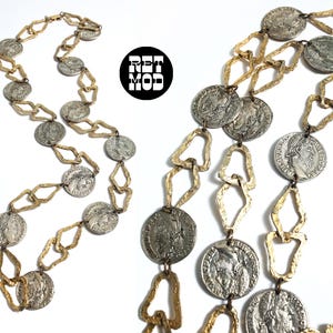 May include: A vintage necklace featuring silver-toned coin pendants and gold-toned geometric links. The coins display detailed relief portraits. The necklace is displayed on a white background. The logo "RET MOD" is visible.