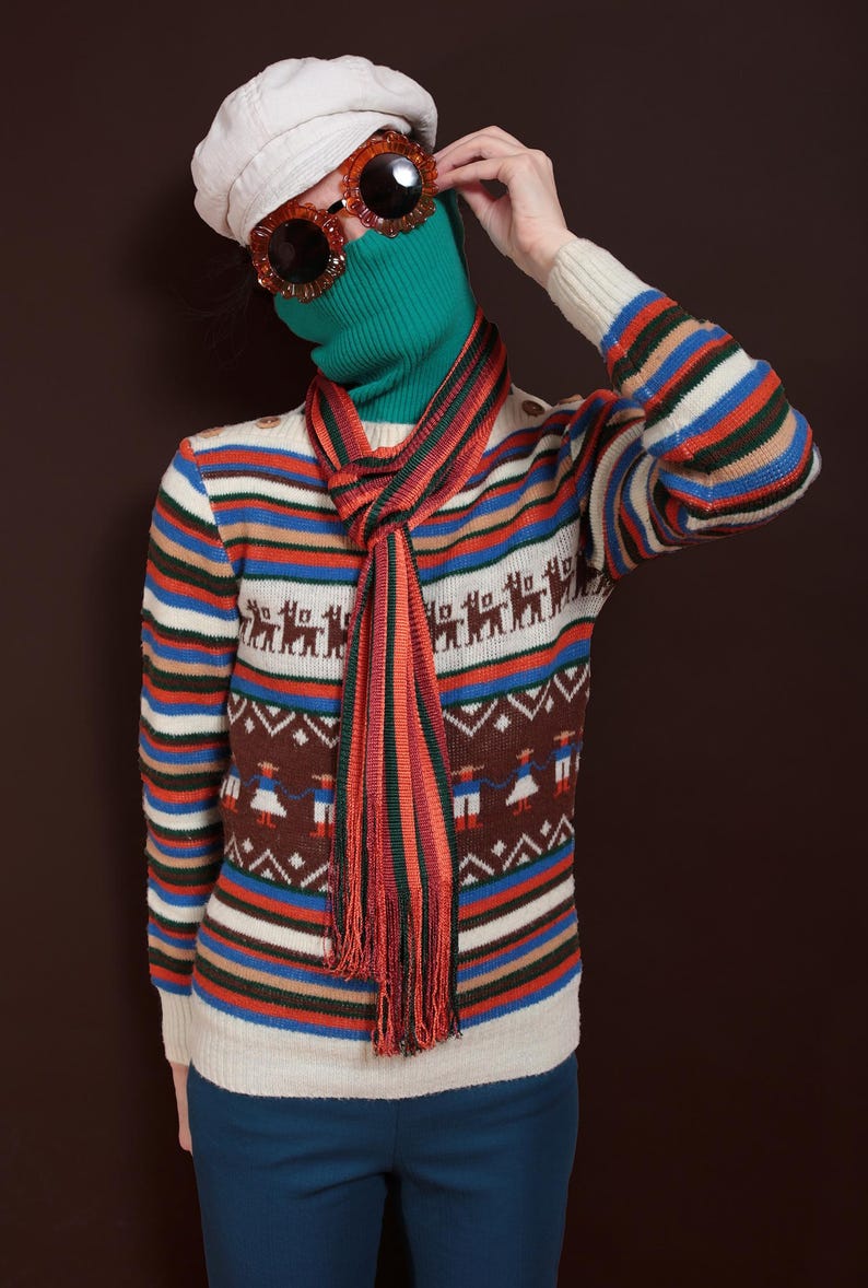 May include: A person wearing a vintage-style outfit. The ensemble includes a cream-colored beret, oversized orange sunglasses, and a green turtleneck. A striped scarf and a sweater with a geometric and animal pattern complete the look. The sweater has horizontal stripes in various colors.