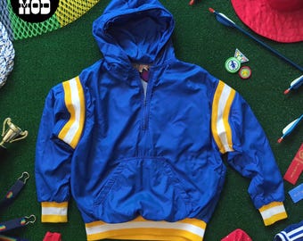 Iconica giacca sportiva vintage anni '80 blu con cappuccio e finiture a righe gialle e bianche.