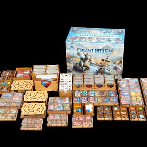 Könnte beinhalten: Ein Frosthaven Brettspiel-Boxset mit einem umfassenden hölzernen Ordnungssystem. Das Set enthält mehrere lasergeschnittene Holztabletts und Behälter, die mit verschiedenen Spielkomponenten, Spielsteinen, Karten und Markern gefüllt sind.