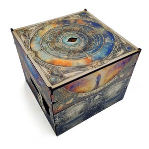 May include: A wooden box with a colorful, abstract design. The top of the box features a circular pattern with a central eye and the text "The World of Prima Mas".