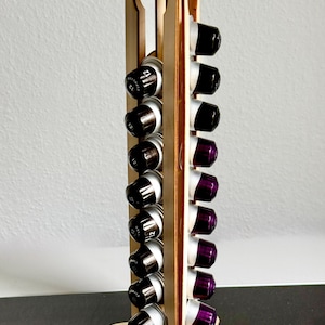 May include: A wooden coffee pod holder with a rectangular design. The holder has slots to hold coffee pods, with a mix of black and purple pods visible. The base of the holder has the word "STATION" and "COFFEE" etched into the wood.