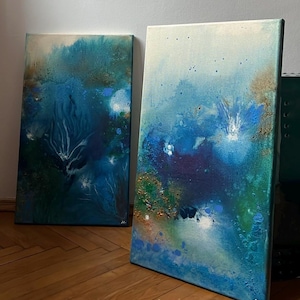 Può includere: Due dipinti astratti su tela. L'opera presenta una miscela di blu, verdi e oro, creando un senso di profondità e movimento. I dipinti hanno un aspetto strutturato, con pennellate e variazioni di colore visibili. Il tema generale ricorda le scene sottomarine.