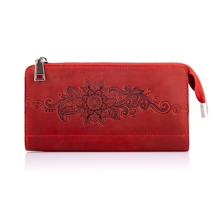 May include: A red leather wallet with a floral design. The wallet has a zip closure and a red wrist strap. The floral design is embossed in black and features a central flower with surrounding intricate patterns.