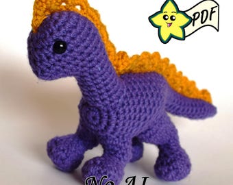 May include: A purple crocheted dinosaur toy with a textured orange spine and a black bead eye. The figure features a long neck and a tail. A yellow star graphic with the text PDF is in the upper right corner, and the text No AI is at the bottom.