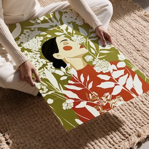 Vertical botanical portrait of a serene woman in side profile with closed eyes, black hair in a low bun, warm orange cheek and red lips, surrounded by cream flowers and leafy branches against an olive green background.