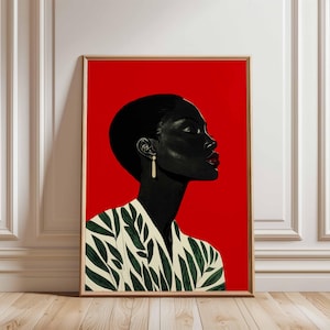 Op de afbeelding: Een ingelijste kunstdruk met een profiel van een persoon met een donkere huid, kort haar en rode lippenstift tegen een felrode achtergrond. De persoon draagt een wit en groen patroon top en een gouden oorbel. Het kunstwerk is ingelijst.