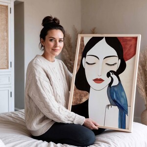 Elegant contemporary artwork featuring a woman in a calm, meditative pose with closed eyes and smooth pale skin. Her long black hair frames her face in clean lines. A vibrant blue parrot perches near her shoulder, its layered feathers creating depth and texture. The warm neutral background of beige and soft terracotta enhances the quiet, intimate mood of the scene.